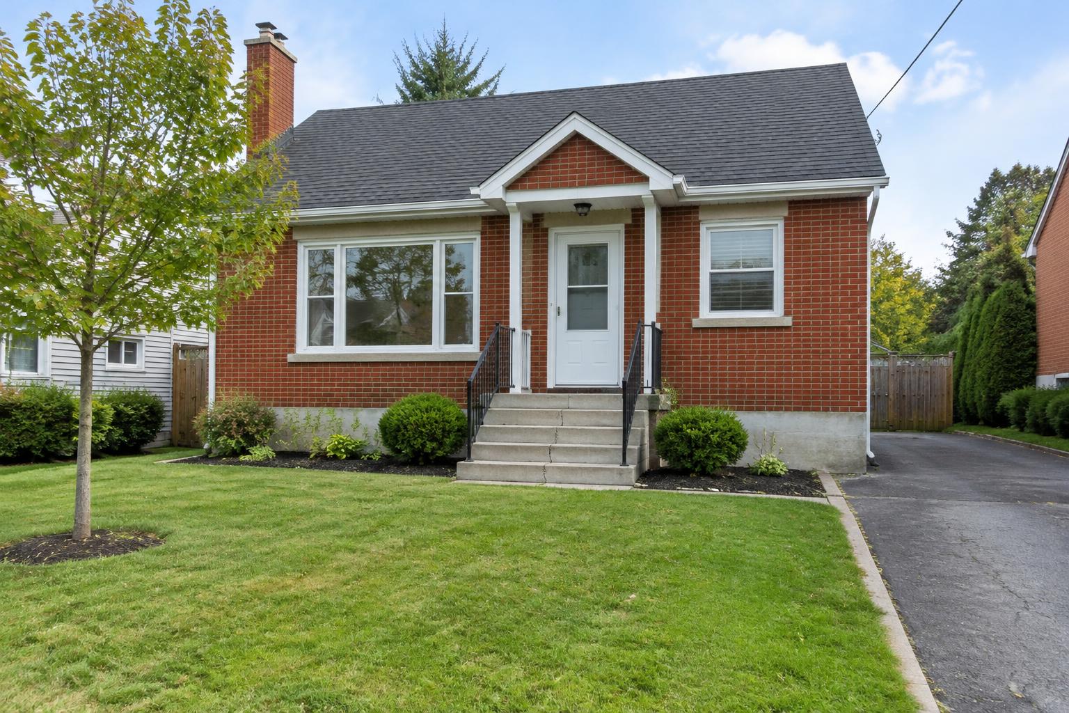 Brick house showing front facade, steps, driveway and grounds